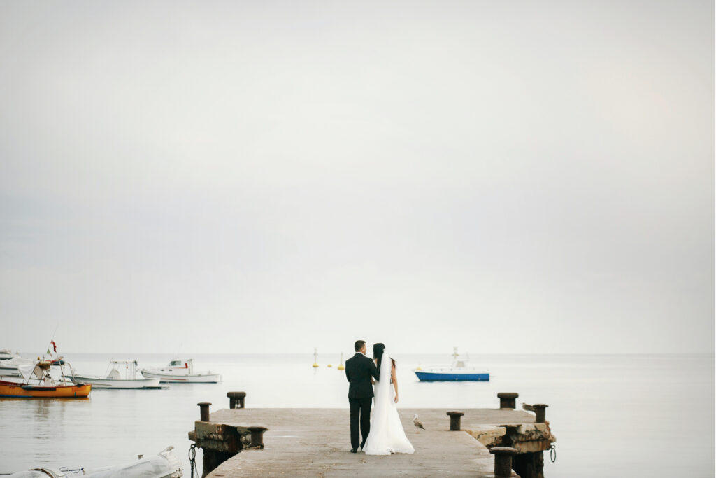 Look from behind at wedding couple walking along the harbor to t
