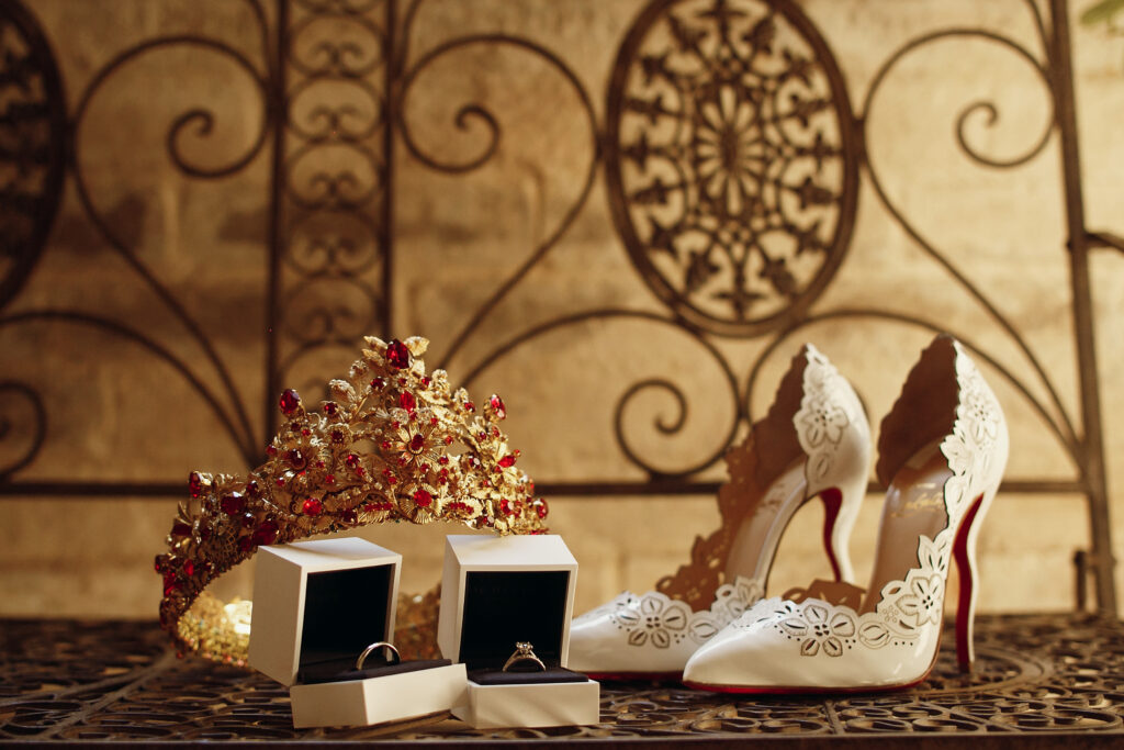 Golden crown with red stones, wedding rings and bride's shoes st